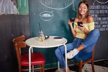 Young woman enjoying coffe alone in a cafe while chatting