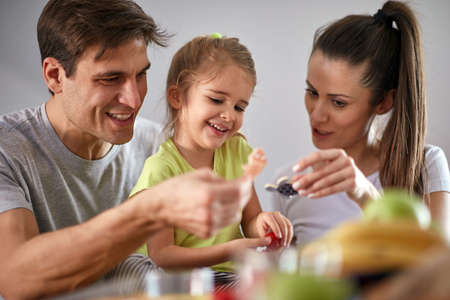 Joyful parents playing together with their daughter at home