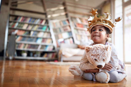 A cute little thoughtful girl playing on the floor in a relaxed atmosphere at home. Family, together, love, playtimeの写真素材