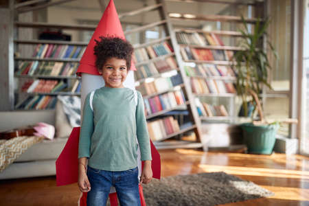 A little boy with a rocket toy on his back is posing while playing in a relaxed atmosphere at home. Home, game, childhoodの写真素材