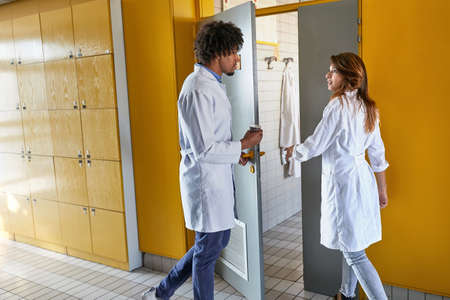 Two young interns entering dressing room together after shift