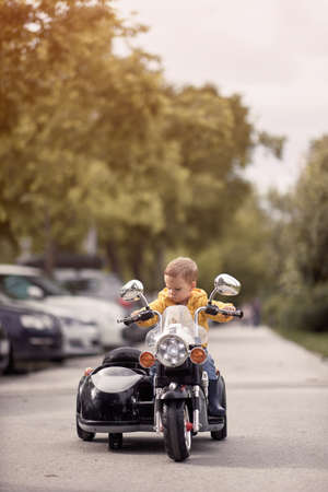 caucasian toddler sitting on a replica of motorcycle. electrical toyの写真素材