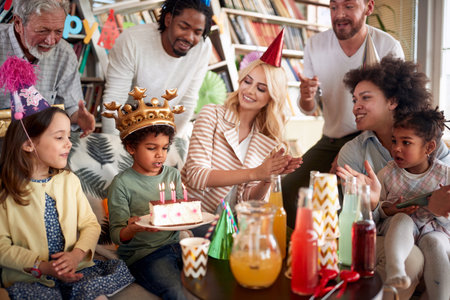 Family and friends singing a birthday song to a little celebrant at his birthday party in a festive...