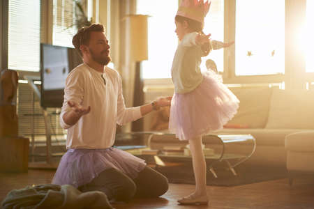 A young father correcting his little ballerina posture while they have a ballet training in a relaxed atmosphere at home. Family, ballet, trainingの写真素材