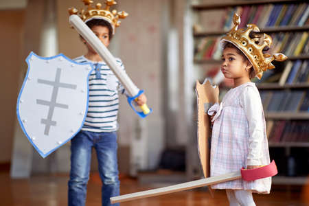 A little brother and sister dressed like knights are having a good time while playing in a cheerful atmosphere at home. Family, home, playtimeの写真素材