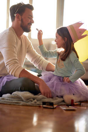 A little girl wants to put a make up on her father's face while they are preparing for a ballet training in a relaxed atmosphere at home. Family, ballet, trainingの写真素材