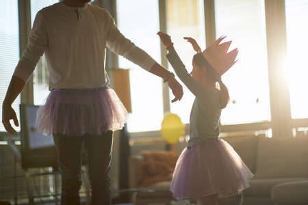 A little daughter and her father dancing while they having a ballet training in a relaxed atmosphere at home. Family, ballet, trainingの写真素材