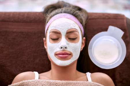 Cosmetic facial mask applying on face of beautiful woman with closed eyesの写真素材