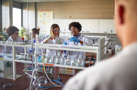 Young colleagues in a protective gear love to work with chemicals in a relaxed atmosphere at the university laboratory. Science, chemistry, lab, peopleの写真素材