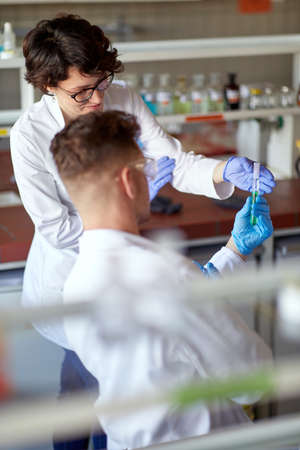 Young scientists observing the chemical in the test tube at the sterile laboratory environment. Science, chemistry, lab, peopleの写真素材