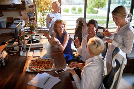 Group of happy female colleagues eating together on a break