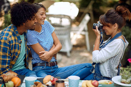 A girl is taking photo of her friends at the bar's backyard on a beautiful weather. Quality...