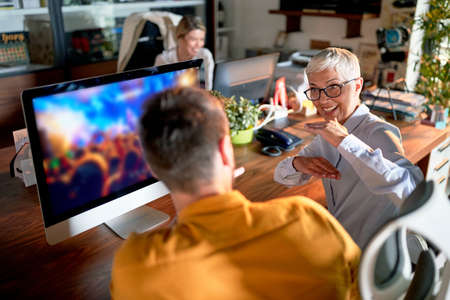 Young new businessman being mentored by senior female partner in the officeの写真素材