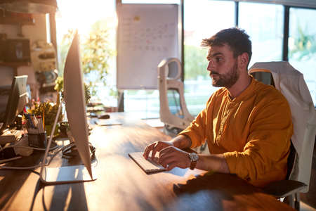 A young male office worker is focused on the job at the desk in a working atmosphere in the office....