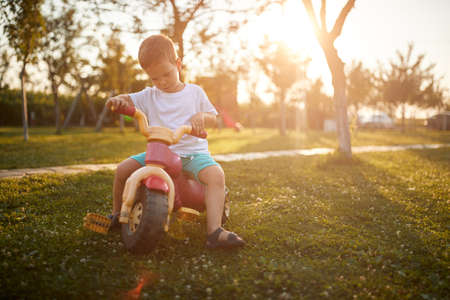 A little boy riding a bike in the yard in the farm on a beautiful sunny day. Farm, countryside, summerの写真素材