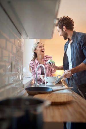 image  of young caucasian adult couple having fun while washing dishesの写真素材