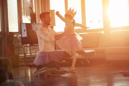 A young Dad loves to work with his little daughter in a beautiful atmosphere at home on her ballet moves. Family, together, homeの写真素材
