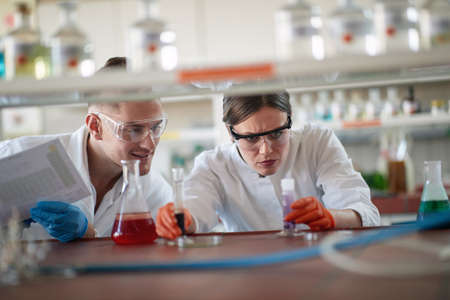 Young chemistry students in a protective gear analyze chemical reaction in a working atmosphere in the university laboratory. Science, chemistry, lab, peopleの写真素材