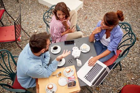 Three happy friends having coffee together at cafeの写真素材