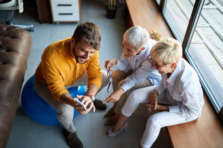 A young male businessman is watching a smartphone content with his elderly female colleaguesの写真素材