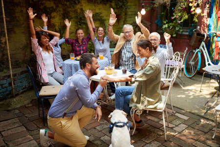 A group of cheerful friends congratulating their young friend's engagement at a party