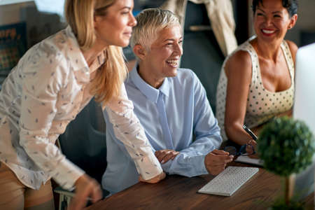Cheerful female colleagues sitting at the desk in a pleasant atmosphere at the office and and...