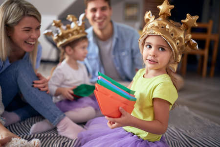 A little girl posing for a photo while playing with her family on the floor in a relaxed atmosphere at home. Family, home, playの写真素材