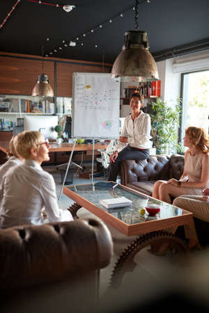 Group of female office staff sitting on the sofa and chatting while taking a break in a relaxed...