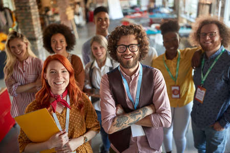 A group of young cheerful creative people are posing for a photo in a pleasant atmosphere at...