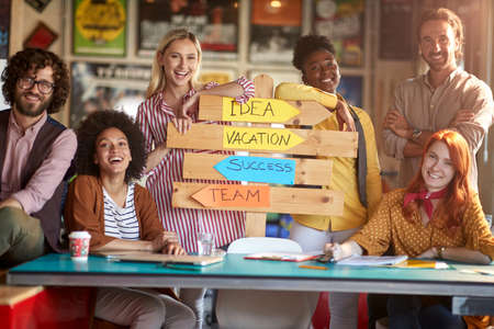 A group of young creative people are posing for a photo in a cheerful atmosphere in the office and presenting their formula for success. Employees, office, workの写真素材