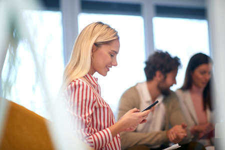 beautiful young caucasian female reading something on her cell phone, smiling.の写真素材