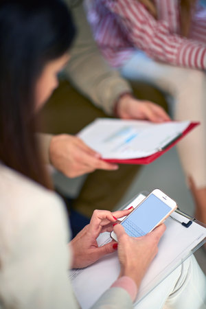 people having business meeting at home of one of them in covid 19 lockdown time. Detail, cropped image, focus on cell phone, copy spaceの写真素材