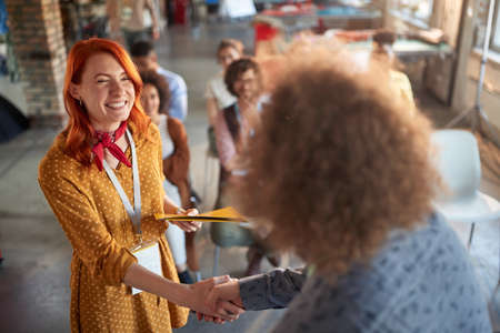 The young woman at office meeting in a pleasant atmosphere is receiving congratulations for merit at work. Employees, office, workの写真素材