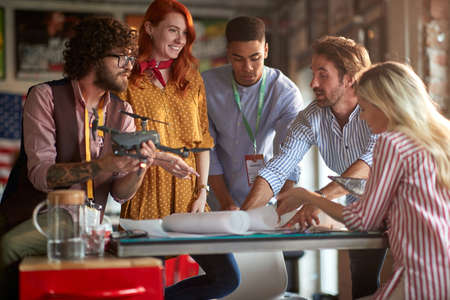 A group of young creative people in a working atmosphere in the office are discussing a plan how they will use a drone. Employees, office, workの写真素材