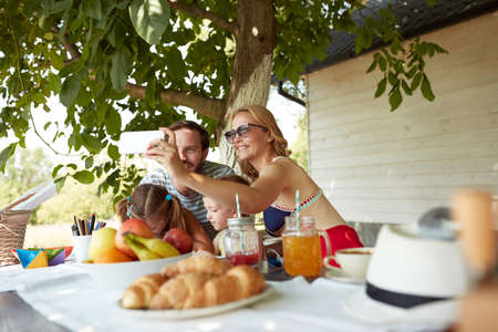 mom taking selfie of family at breakfastの写真素材