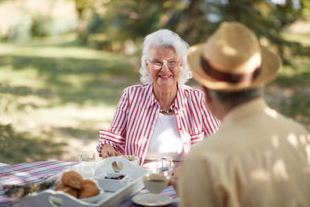 cute caucasian elderly couple enjoy outdoor, having breakfast and coffeeの写真素材