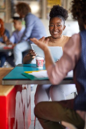 A young female employee is listening to her colleague while working in a friendly atmosphere in the officeの写真素材