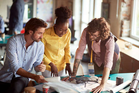 Group of young creative people in a pleasant atmosphere in the office is looking project drafts