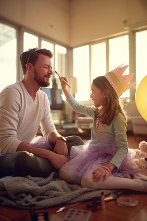 A little daughter love to put makeup on her father's face when they preparing for ballet exercises in a relaxed atmosphere at home. Family, together, homeの写真素材