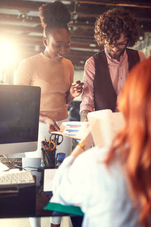 young colleagues looking and analyzing statistic reports together, consulting, exchanging opinions