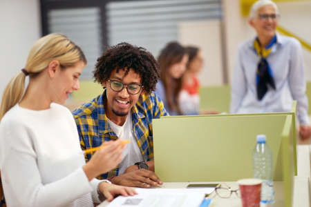 Colleagues helping each other about the lesson at the lecture in a classroom
