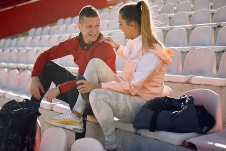 Young sportsman talking to smiling female athlete.の写真素材