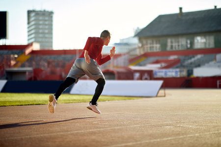 Athletic young man sprinter running on stadium.