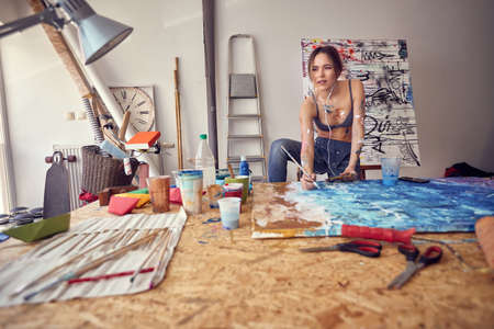 sexy woman artist in underwear drawing on easel  while listen music on mobile.の写真素材