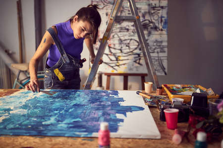 Focused female painter artist creating a new piece in the studioの写真素材