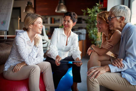 Group of female office staff chatting while taking a break in a pleasant atmosphere at workplace. Business, office, jobの写真素材