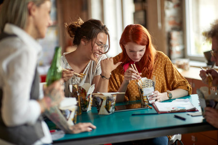 A group of young creative people enjoying lunch during a break in a relaxed atmosphere in the office. Employees, office, workの写真素材