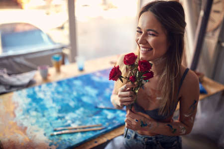 A young sexy and attractive female artist with roses having a good time in a relaxed atmosphere in her studio. Art, painting, studioの写真素材