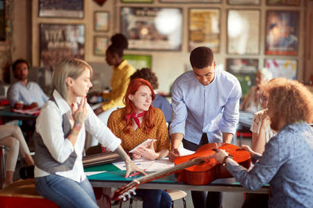 Group of young creative people in a pleasant atmosphere in the office are enjoying a process of designing a new guitarの写真素材