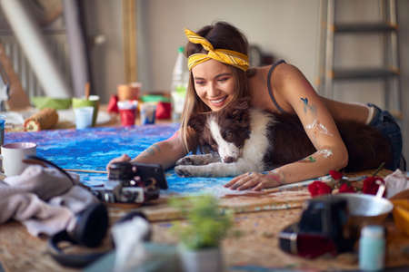 A sexy and attractive female artist is enjoys taking a selfie while spending time with her dog in a relaxed atmosphere in the studio. Art, painting, studioの写真素材